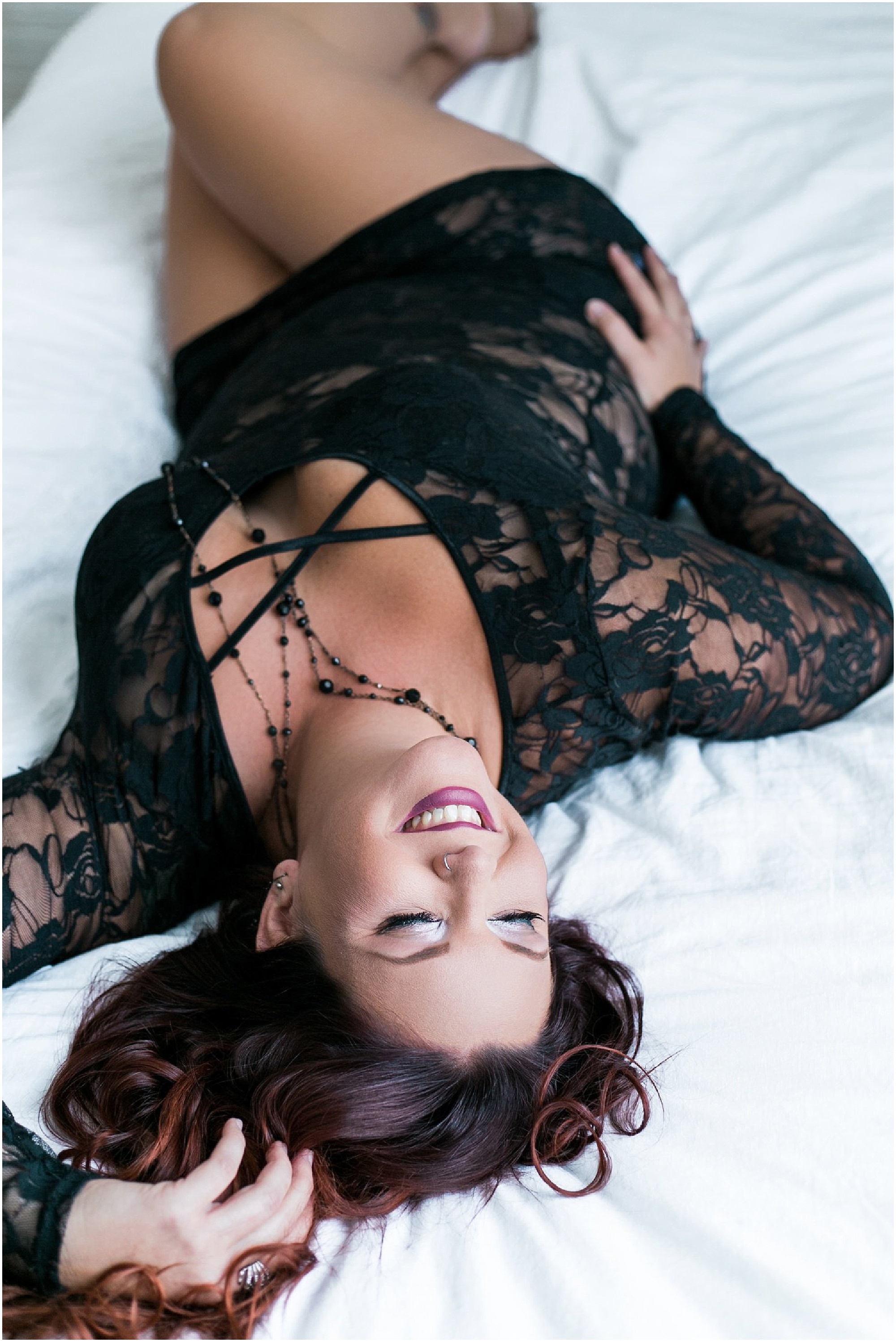 Lindsley's Empowered Boudoir Shoot photo of her lying on the bed in black lace lingerie in our boudoir studio in downtown Sanford.