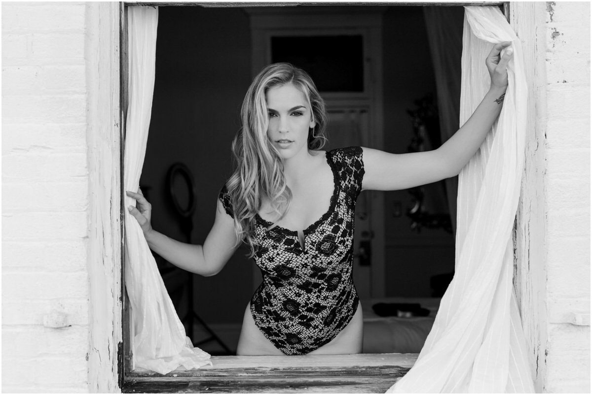 Boudoir session model in black and white photo through a window. 