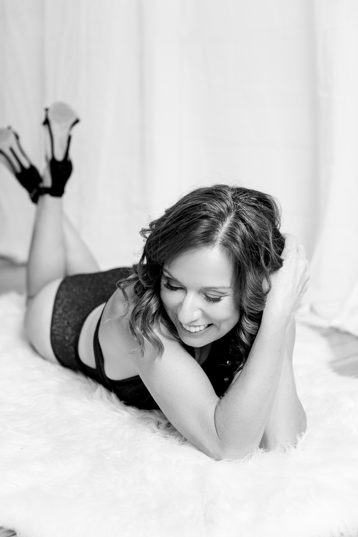Black and white photo of lady laying on the floor at boudoir session. 