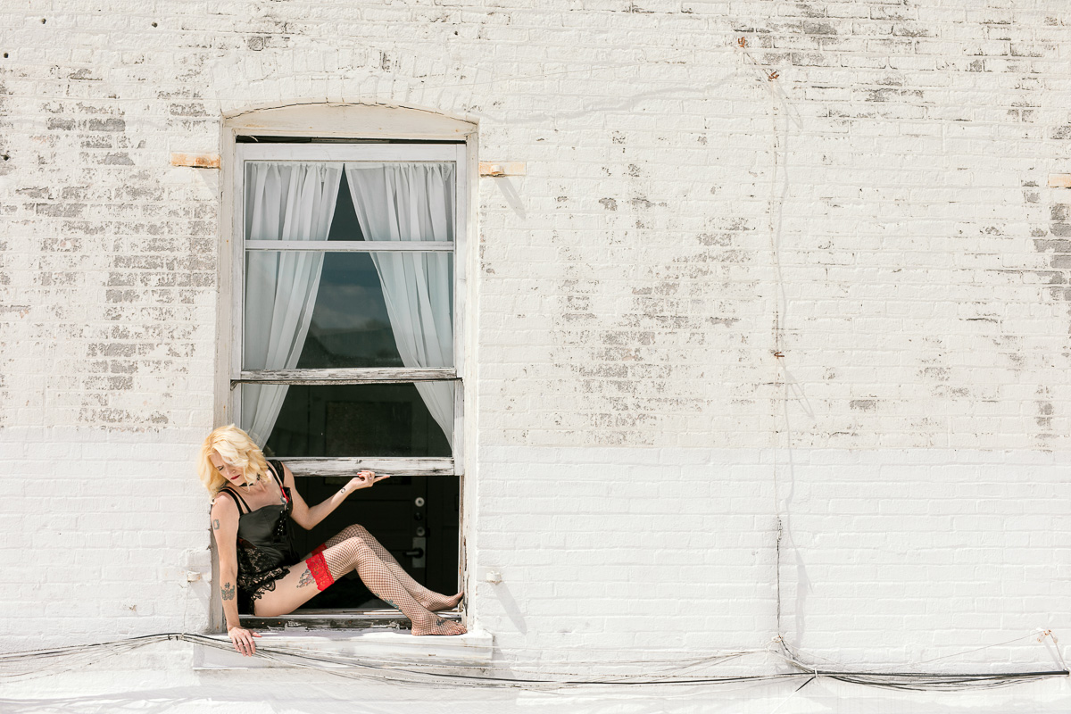 Woman sitting outside on a windowsill. 