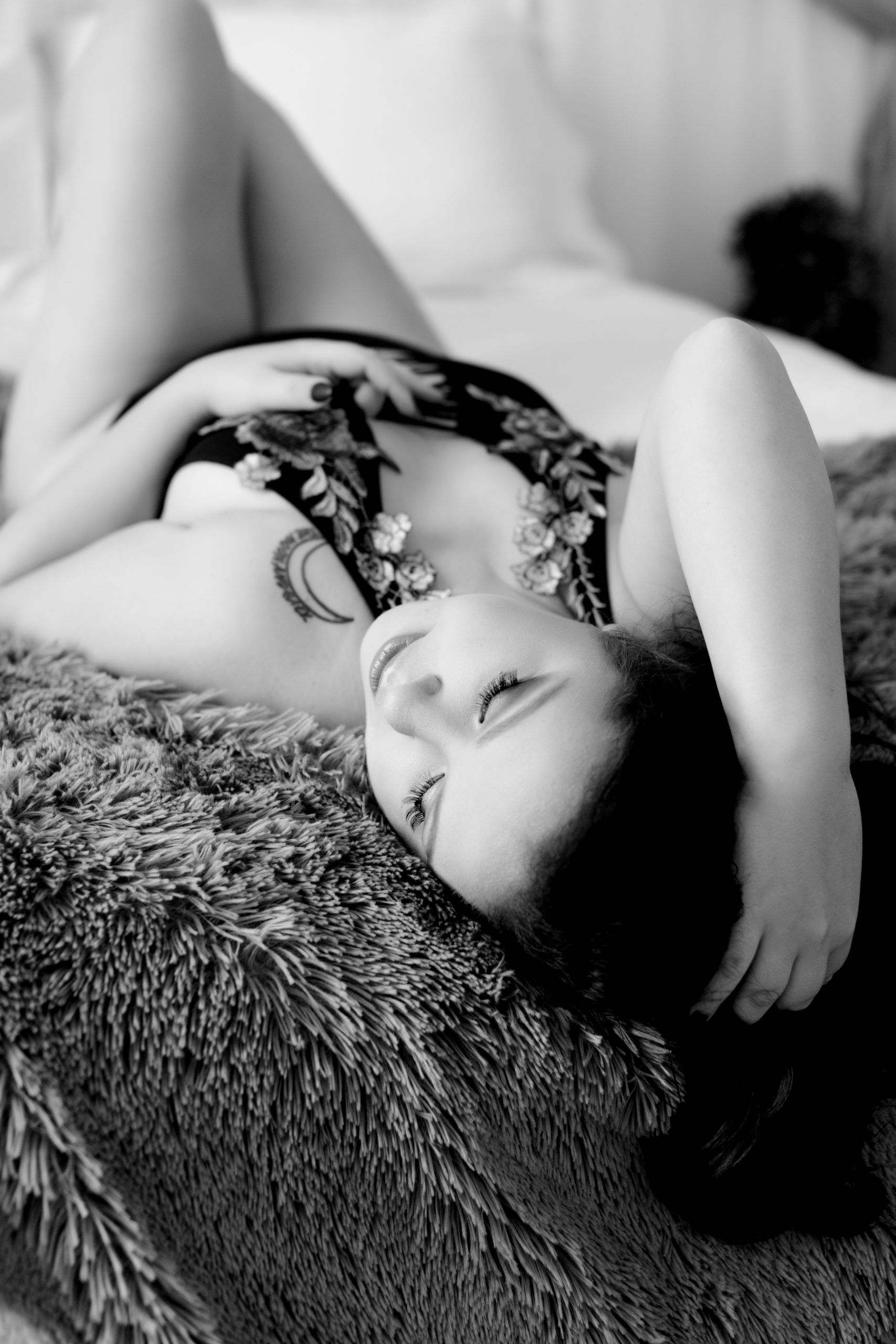 Black and white photo of boudoir model on bed
