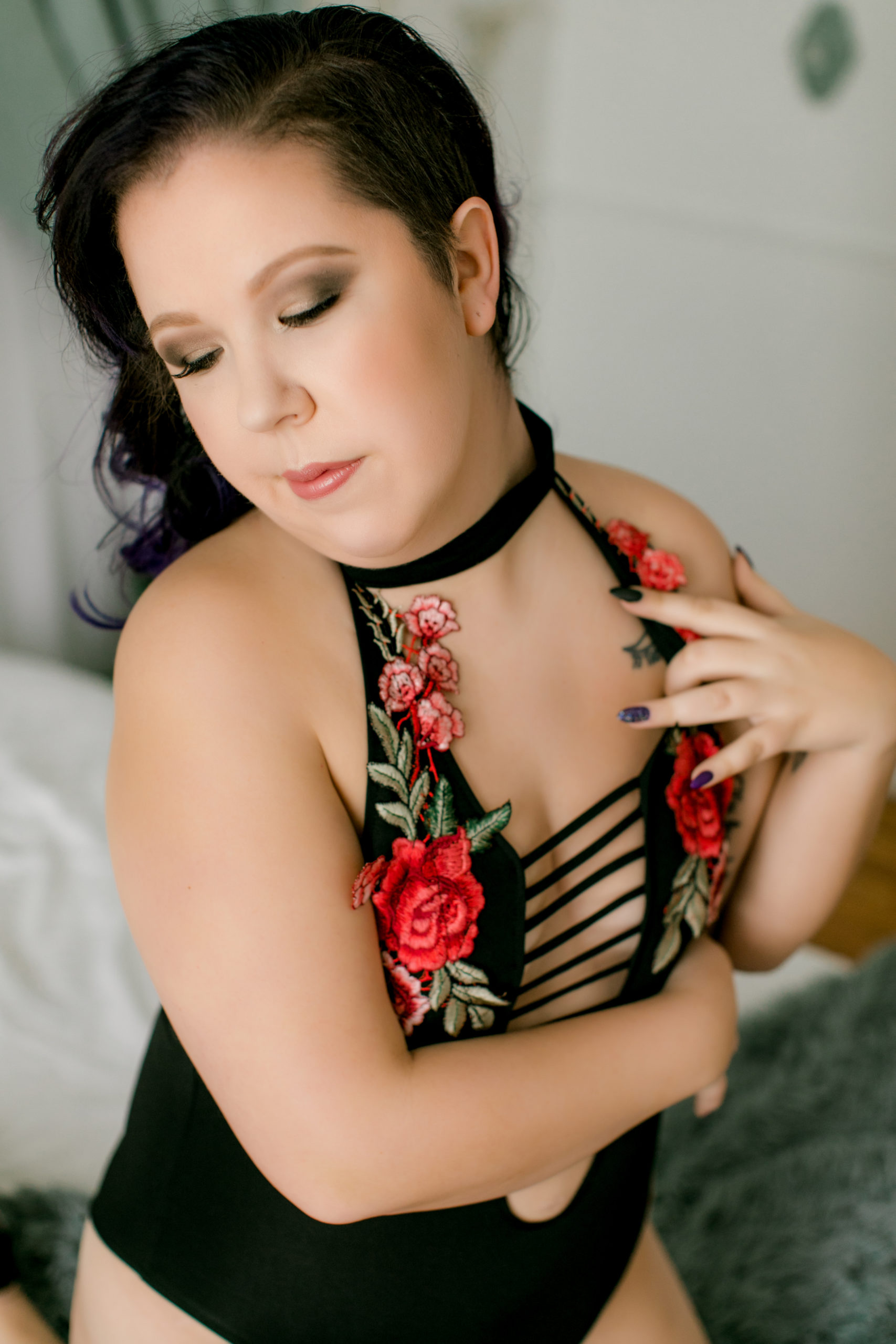 Beauty S in a black bodysuit embellished with red embroidered flowers. 