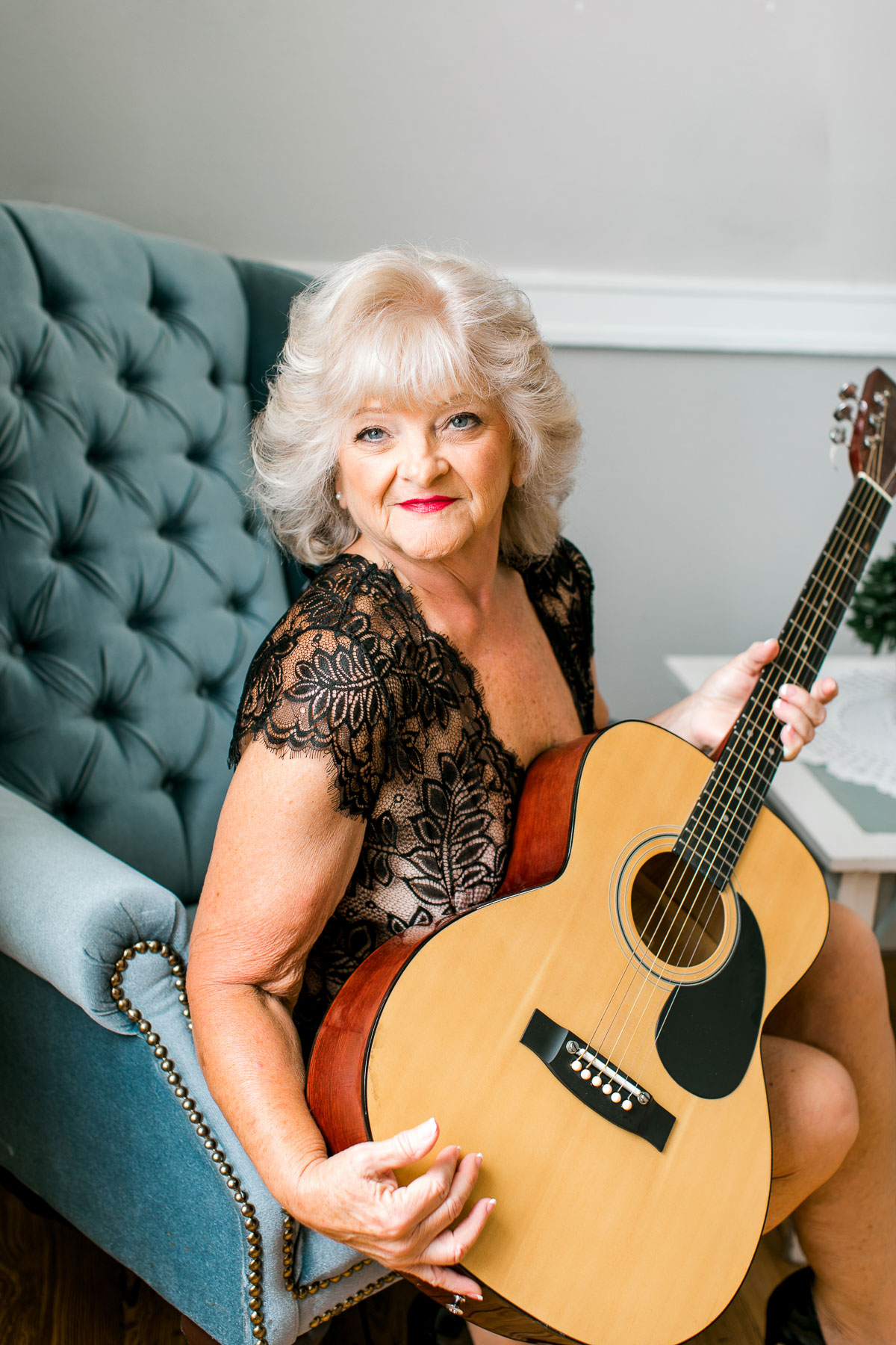 Boudoir woman holding guitar while sitting in chair