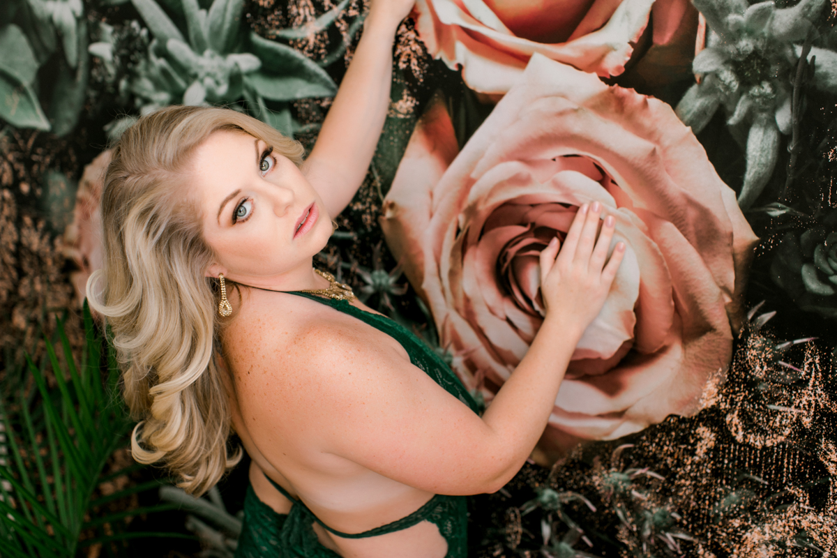 woman up against floral wall in green lace 