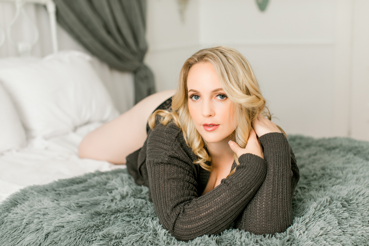woman blond with blue eyes on bed with black lace panty and sweater
