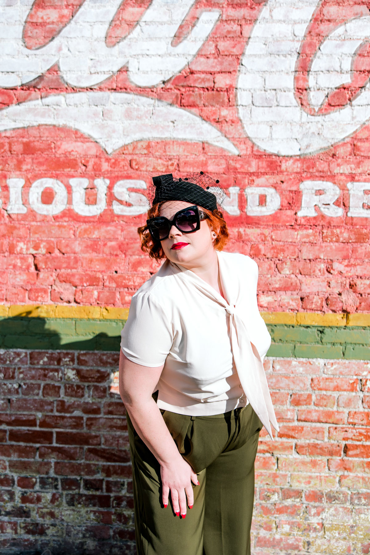 1950's glam photo vintage blouse, black wide frame sunglasses, olive green pants and red nails 