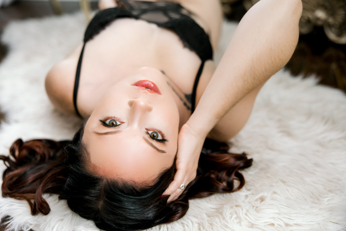 Woman laying on the floor in black lingerie and boudoir bedroom eyes