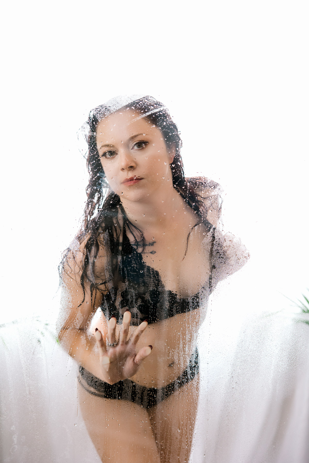 Woman looking out of the shower glass wearing black bra and panties
