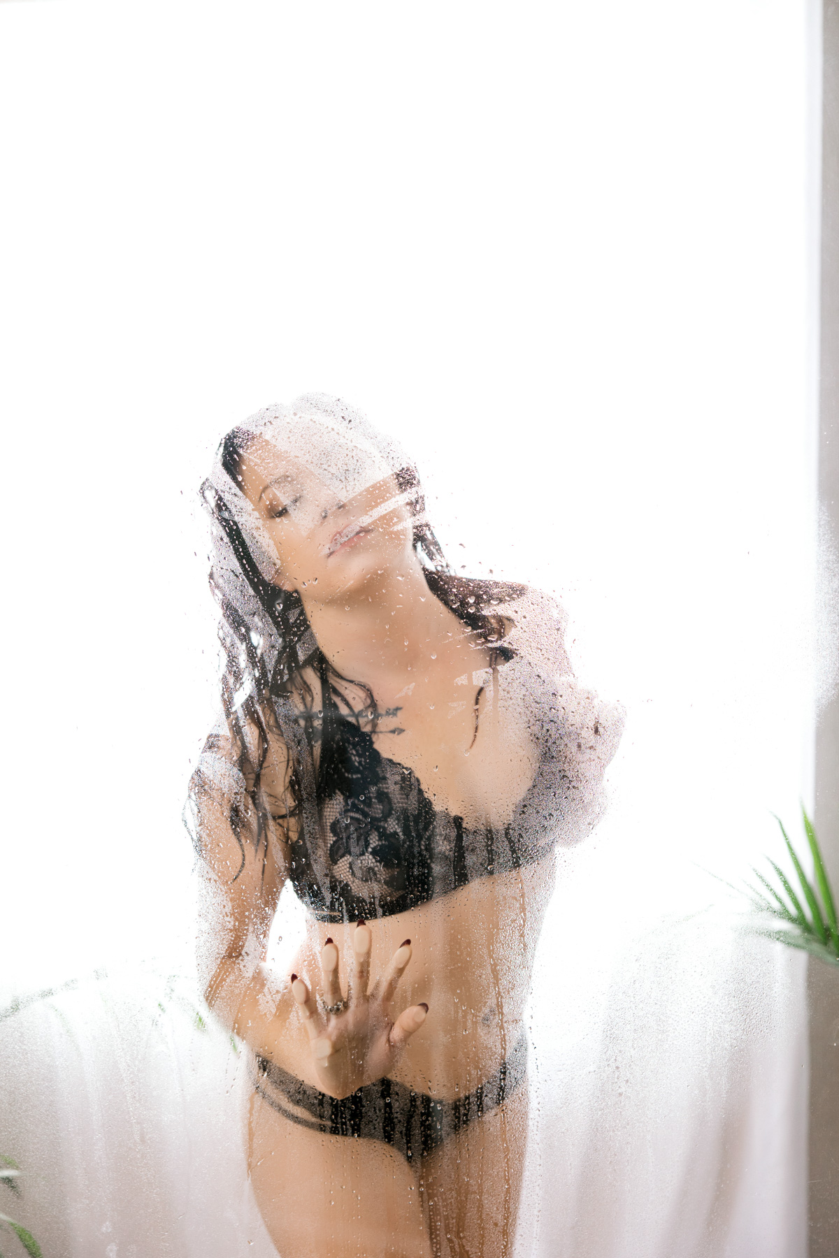 Woman standing in a shower and posing for boudoir session