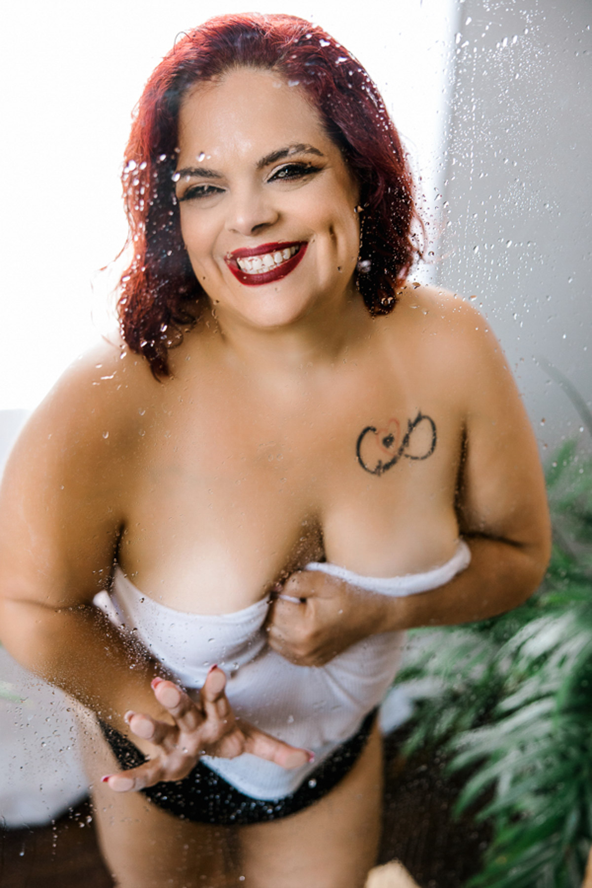 curvy woman in black patines and white top in shower smiling big