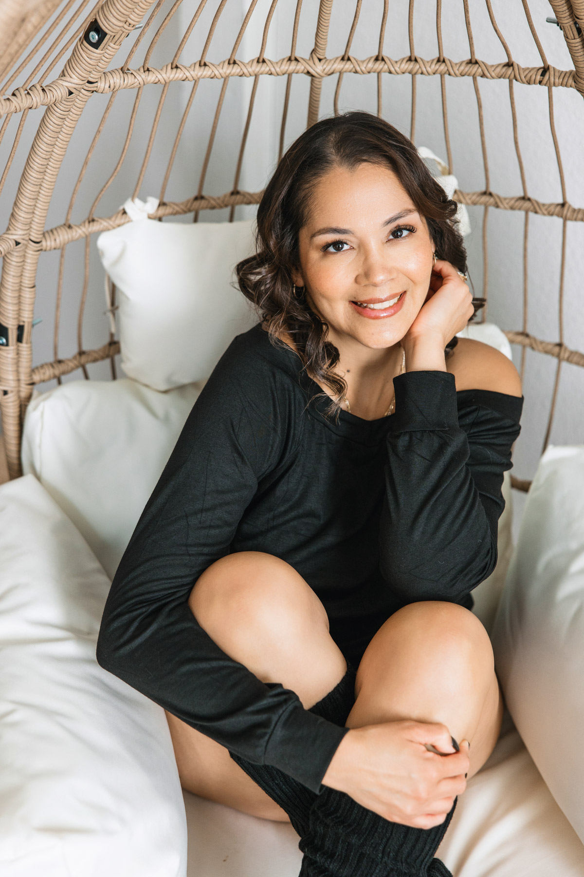 woman sitting on egg chair wearing black sweater and leg warmers
